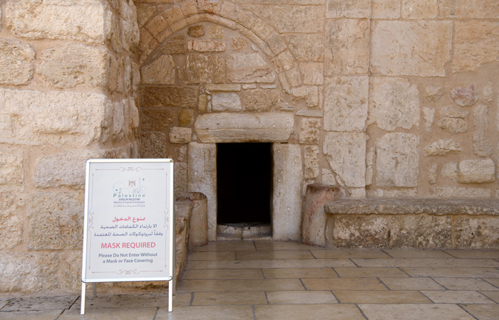 Devant la porte de l'humilité par laquelle on accède à la basilique de la Nativité, un panneau indique que le port du masque est obligatoire pour entrer. ©Nadim Asfour/CTS